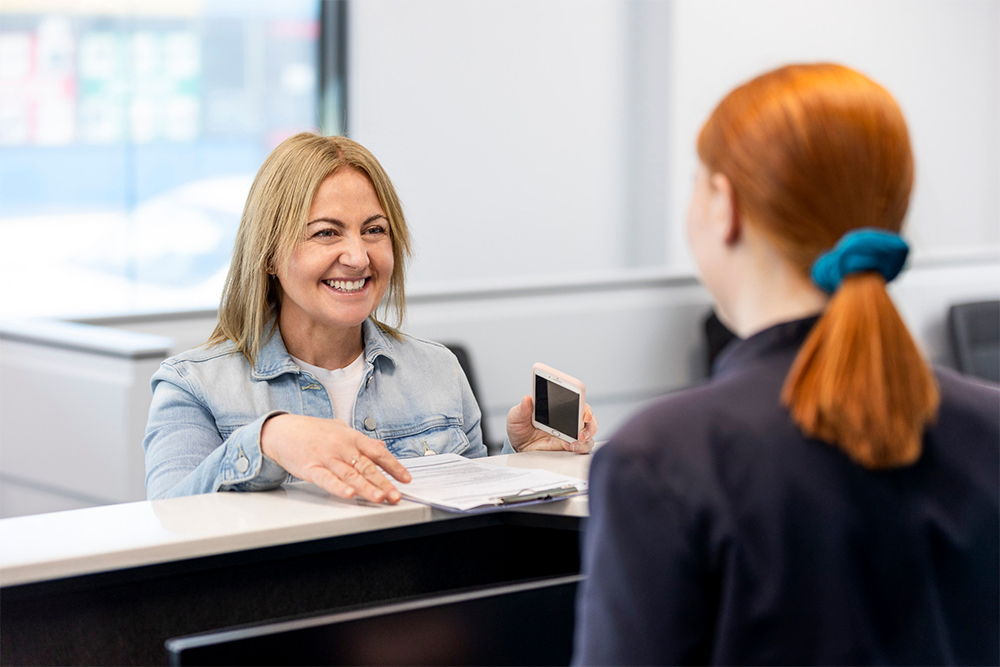 A female patient smiling at the reception desk as she checks in for her scan at IOP