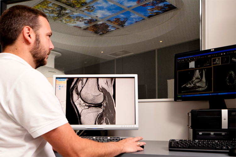 Male radiographer reviewing MRI scans to ensure high quality images are captured.