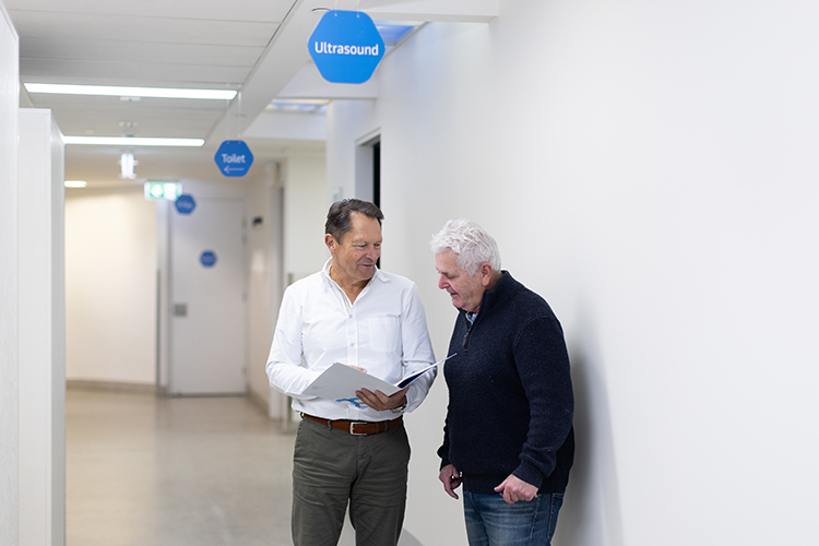 Medical specialist speaking with a patient about an imaging procedure in a clinical corridor