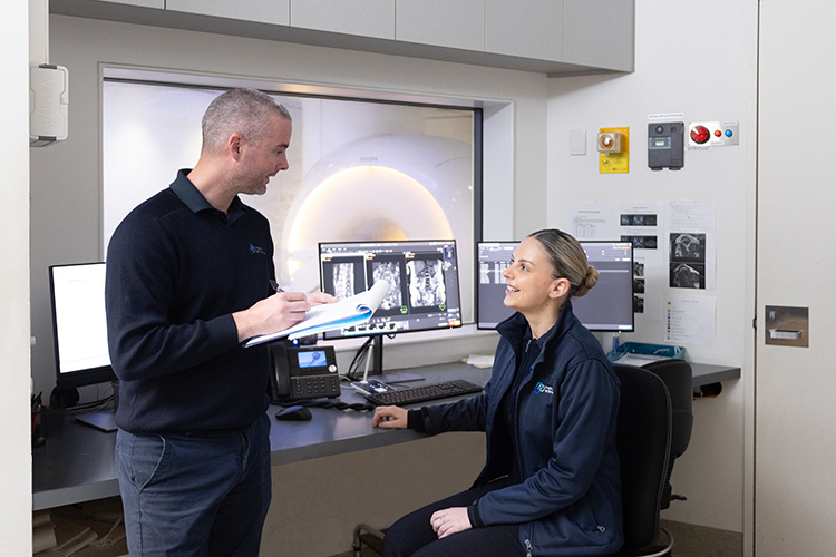 Medical imaging professionals discussing an MRI procedure in the control room